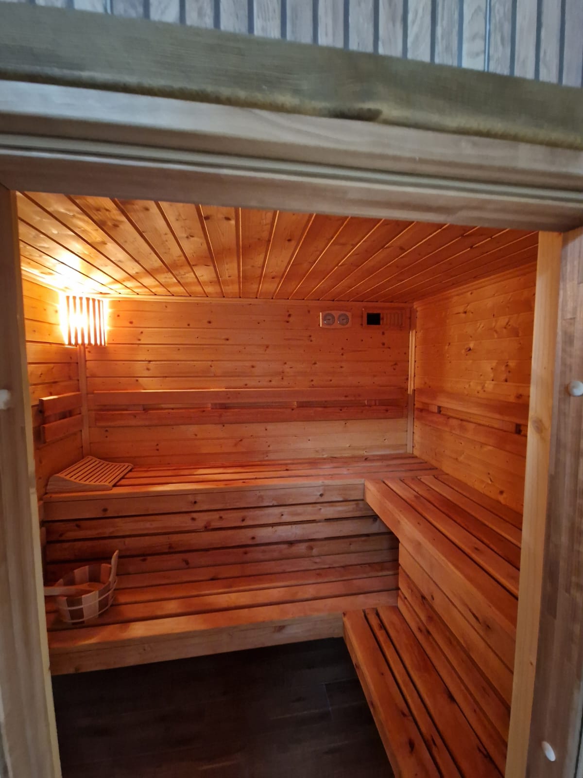 Drewniana sauna z ławami, ciepłym światłem i akcesoriami do saunowania